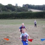 Children running towards a ribbon in a field