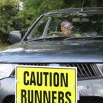 car with caution runners sign