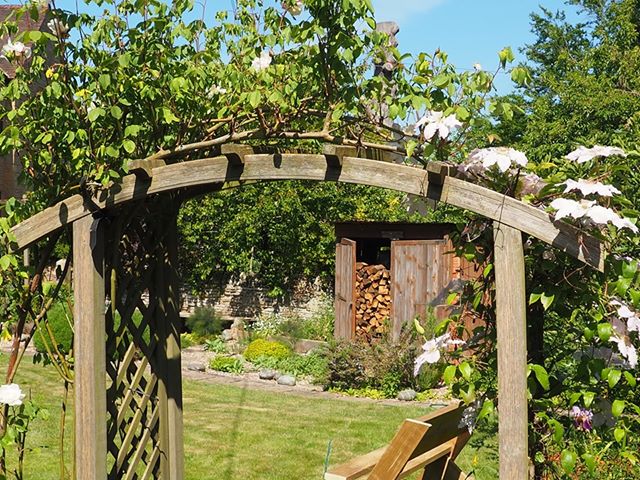 Wooden arch, lawn and log store full of logs