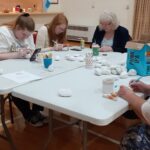 A group of women sitting at a table and painting stones