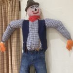 A scarecrow with a red scarf and a blue shirt and waistcoat