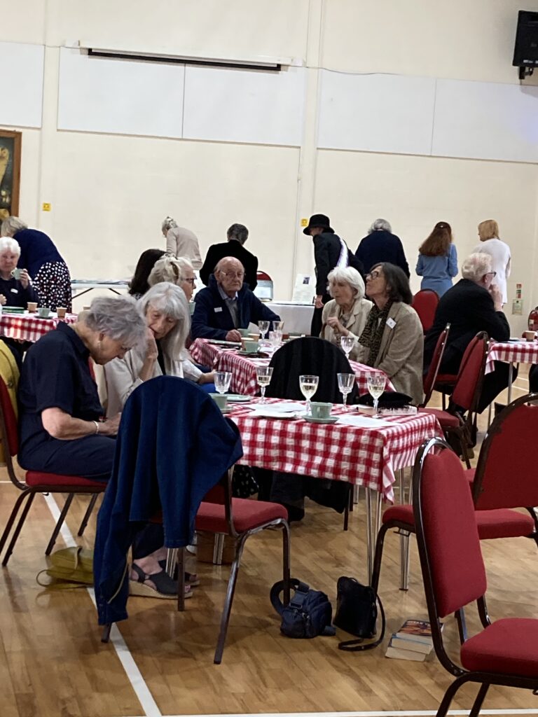 Group of people sitting at tables with red and white tablecloths