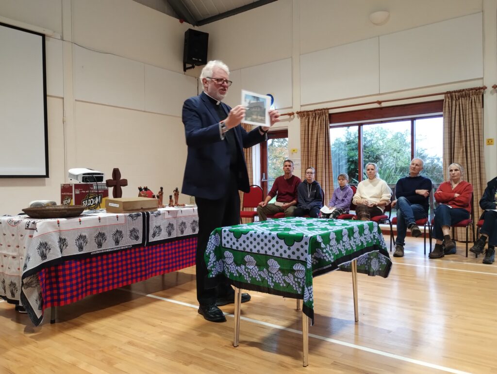 Vicar holding up a picture in front of people sitting in chairs