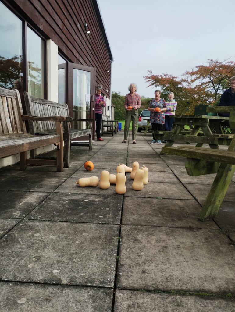 Four women playing pumpkin skittles