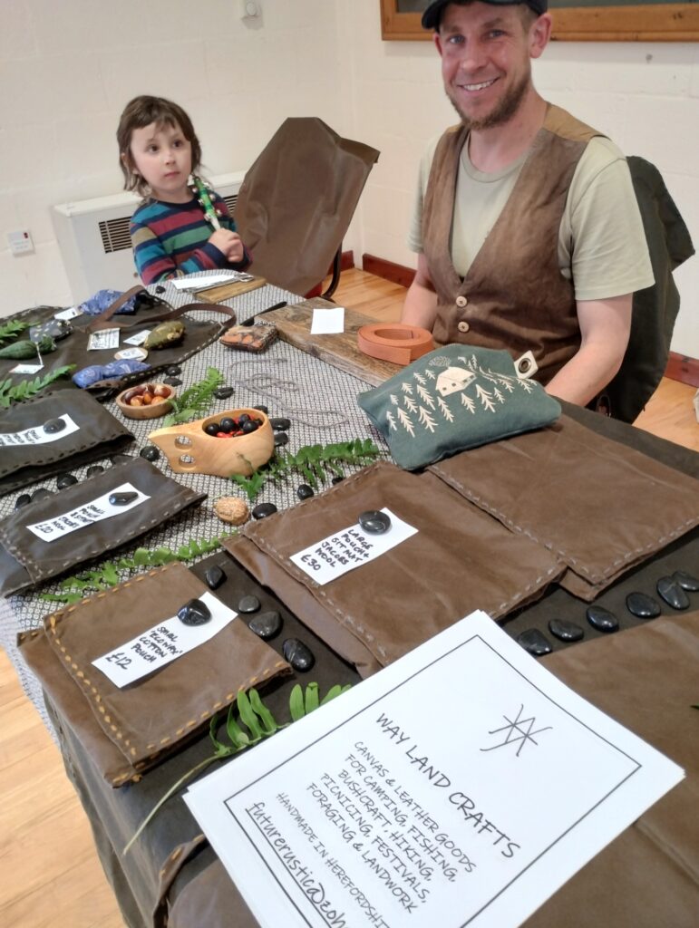 Man and boy smiling behind table with hand crafted goods