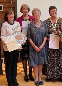 Four women holding certificates and a trophy