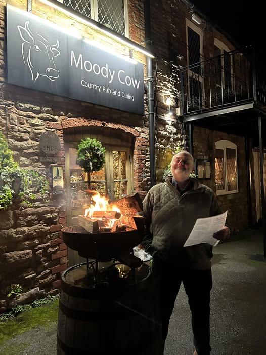 Chris Burgess, the landlord of the Moody Cow singing by a brazier in front of the pub